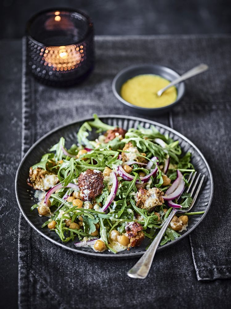 colourful chickpea and falafel salad in a dark bowl on a dark grey tablecloth