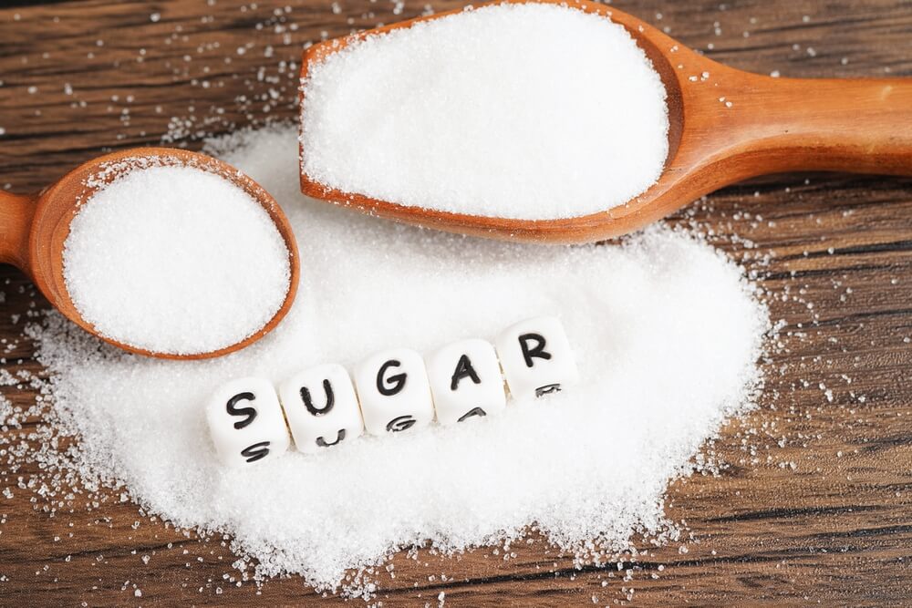 A pile of sugar with the word sugar spelt out on top of it with white cubes